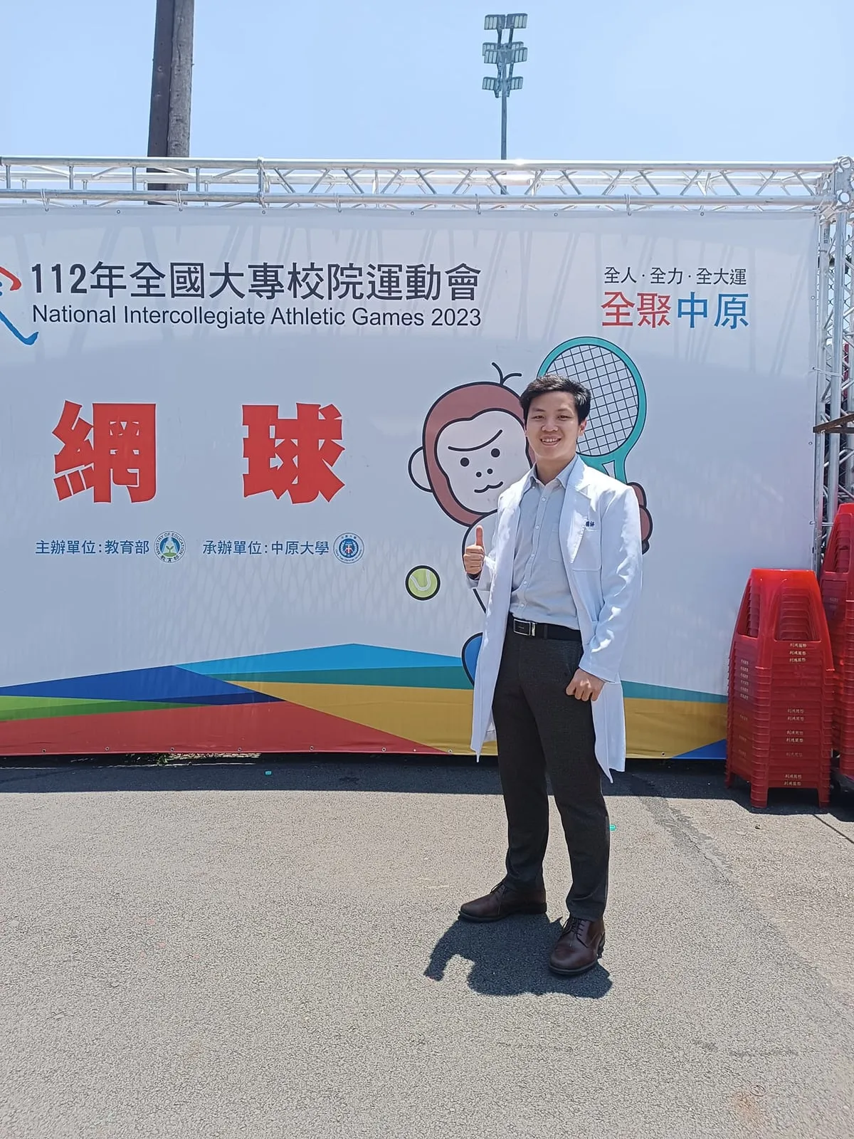 程皓醫師身穿白袍站在全國大專運動會網球場邊